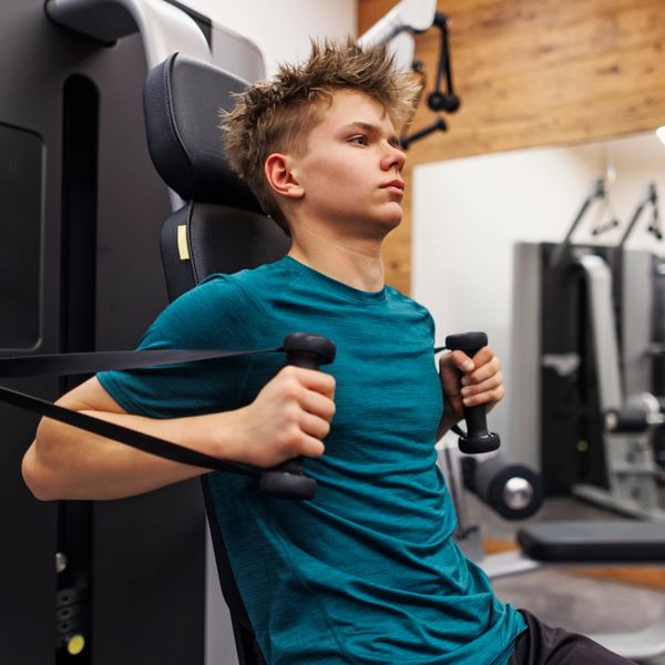 Teen boy focused on strength training using a chest press machine.