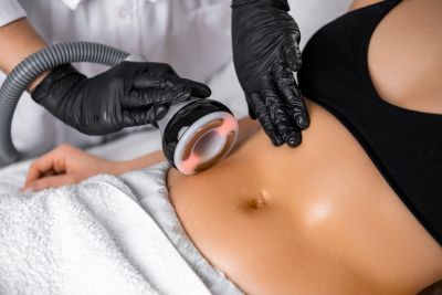 A technician performs a non-invasive body contouring treatment on a woman's abdomen.
