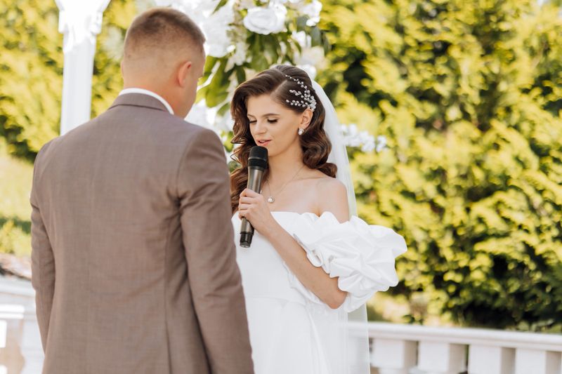 sensitive ceremony of the bride and groom. A happy newlywed couple is standing against the background of a wedding arch, she says yes to him. Wedding vows. The emotional part of the wedding