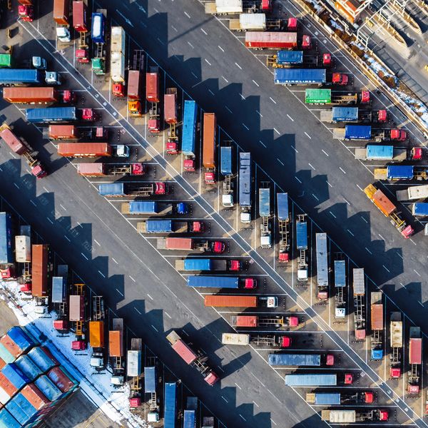 Aerial view of numerous trucks parked in organized rows at a large freight yard.