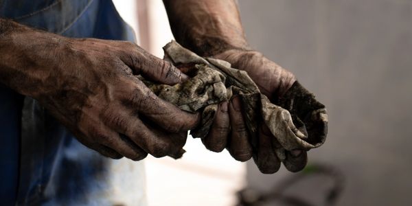 Dirty hands holding a grimy cloth, possibly after mechanical work.