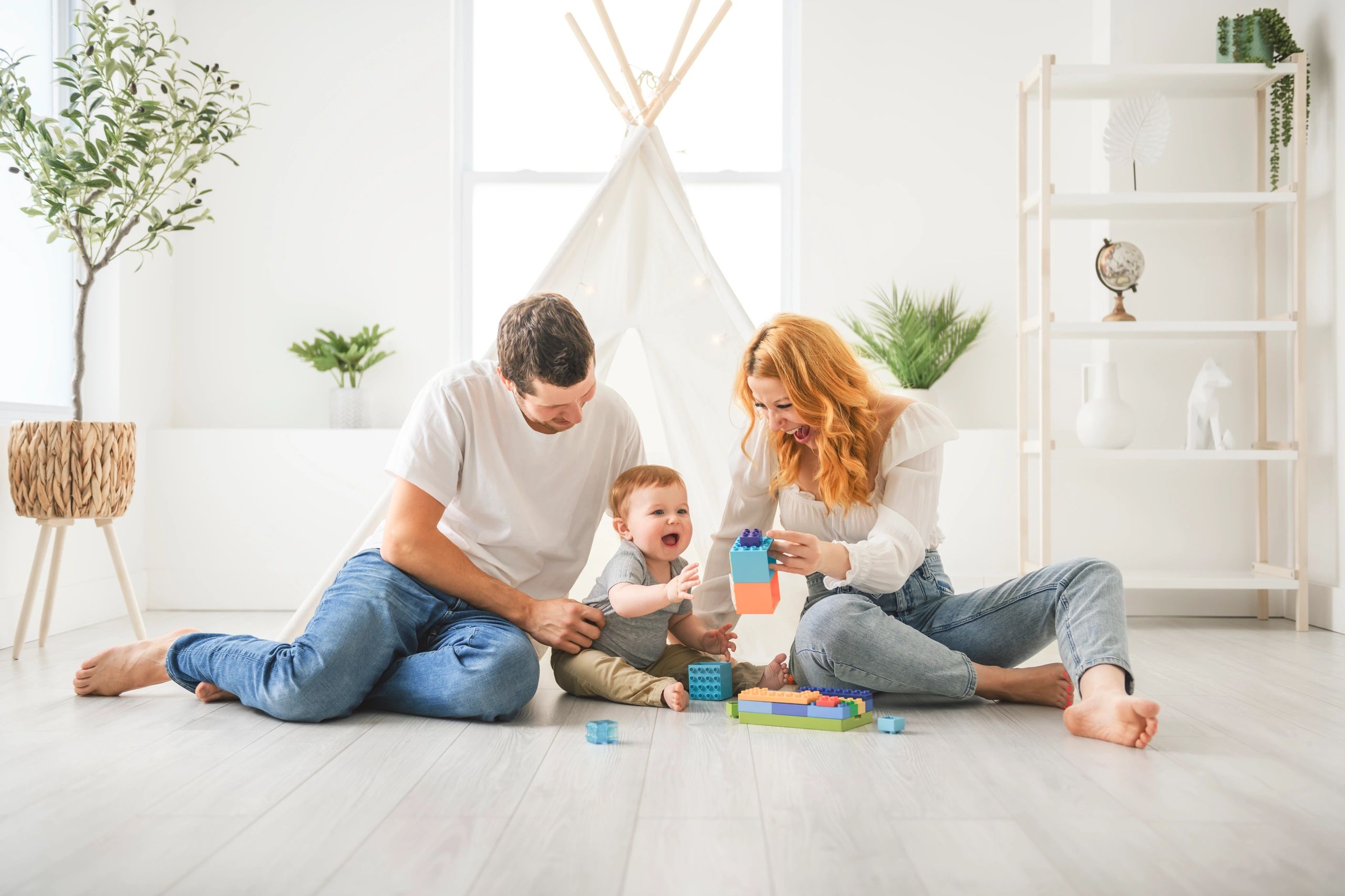 Happy family playing with building blocks on the floor in a bright room.