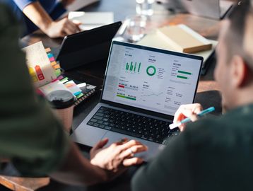 People analyzing data on a laptop screen.