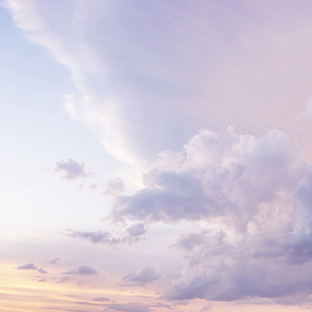 Soft pastel clouds fill a serene sky at dusk.