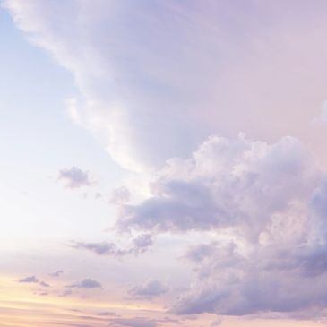 Soft pastel clouds fill a serene sky at dusk.