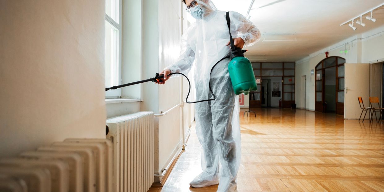 Person in protective suit disinfecting indoors.