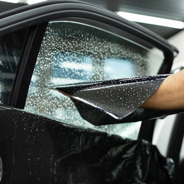 Black putting black film on side and off car