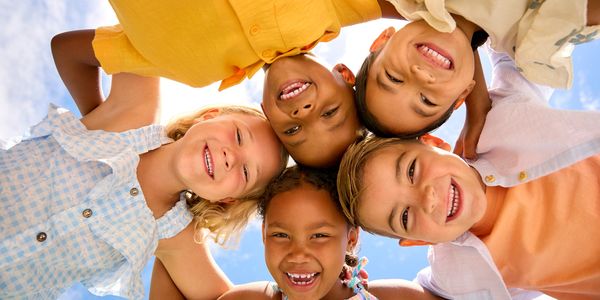 Group of happy children smiling in a circle outdoors.