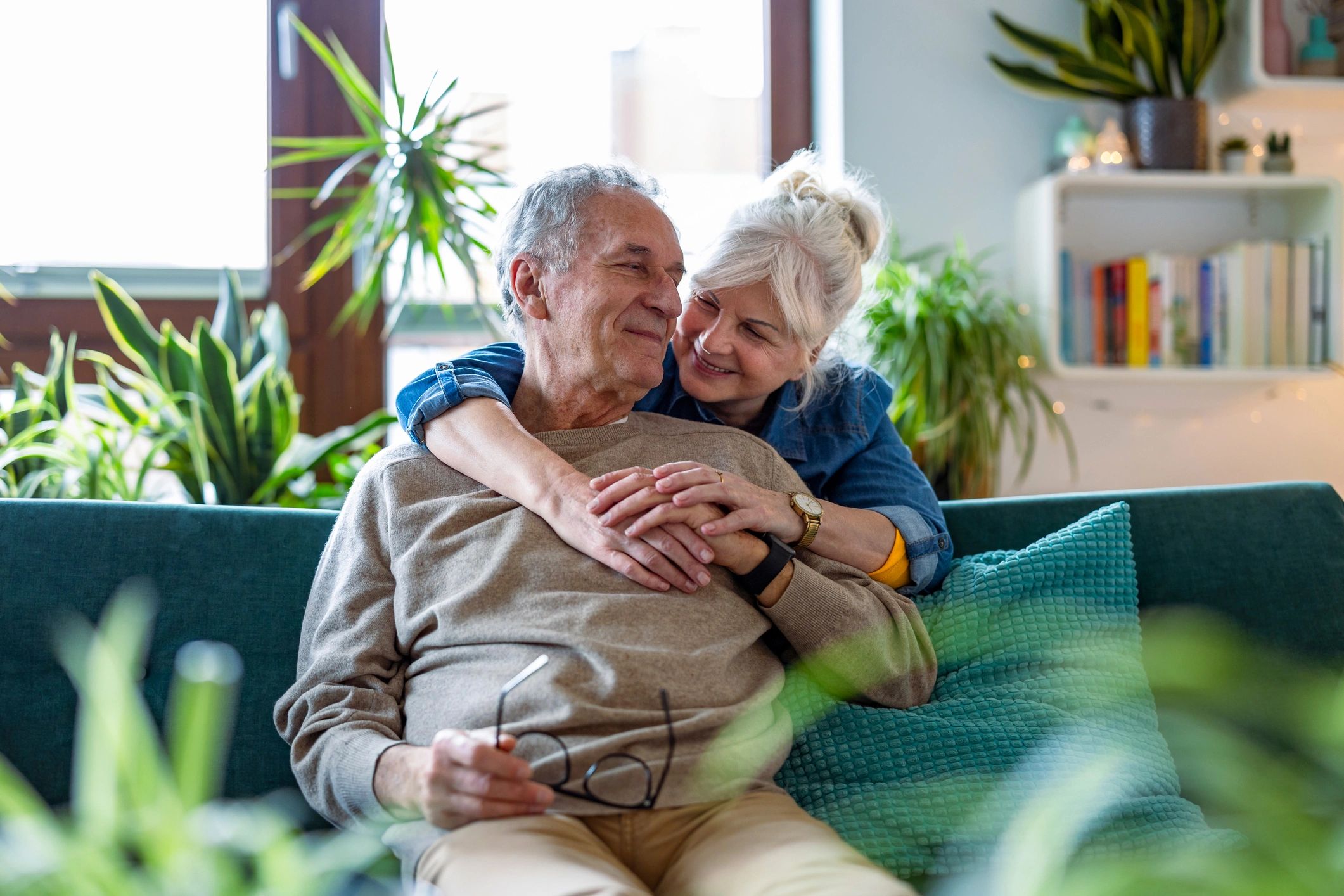 Elderly couple sharing a loving embrace on the couch.