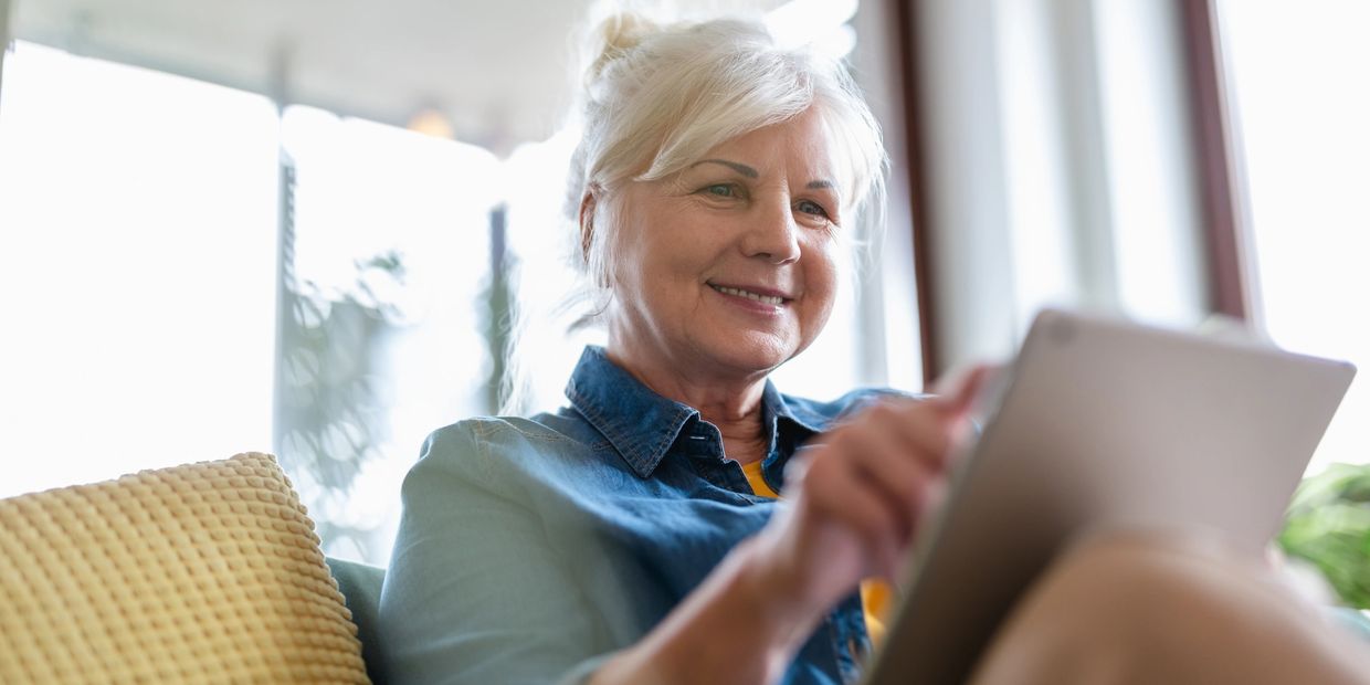 Smiling older woman using a tablet at home.