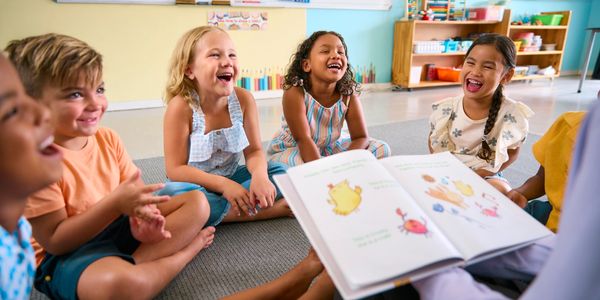 Children sitting in a circle, laughing during storytime.