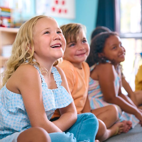 Happy children sitting on the floor, smiling and engaged in an activity.