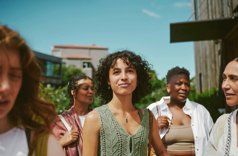 Smiling young woman standing with friends outside after a yoga class on a patio at a wellness retreat in the summertime