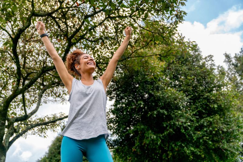 Happy African American female runner celebrating with arms up after a good workout