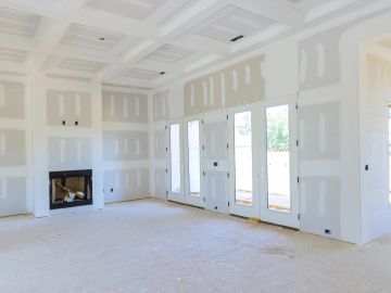 Unfinished room with drywall and fireplace under construction.
