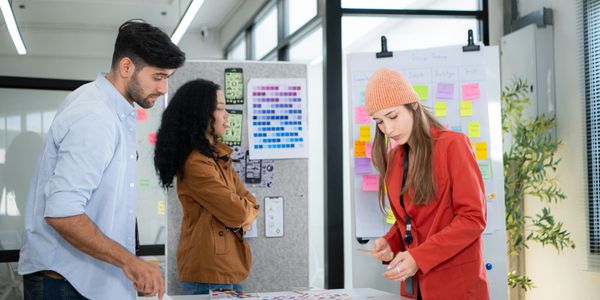 Three colleagues collaborating on a project with sticky notes and charts in a modern office.