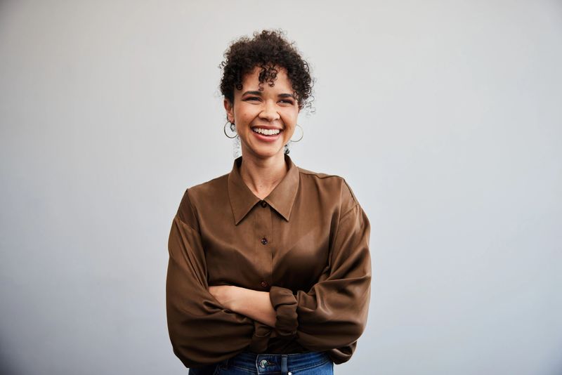 Portrait of a young businesswoman smiling while standing with her arms crossed in front of a white wall in an office
