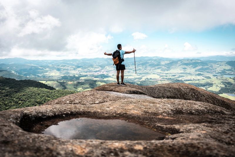 Rear view of a young man with arms outstretched on trail on a mountain