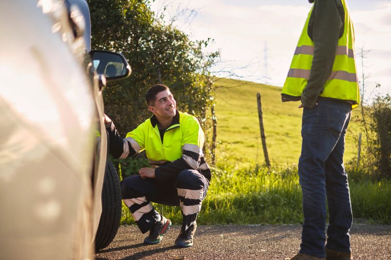 Man receiving roadside assistance from a mechanic after breaking down on the road