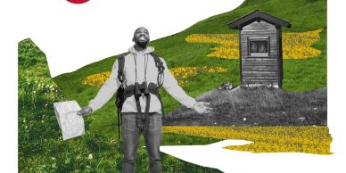 Man hiking with a map near a small wooden hut on a grassy hill.