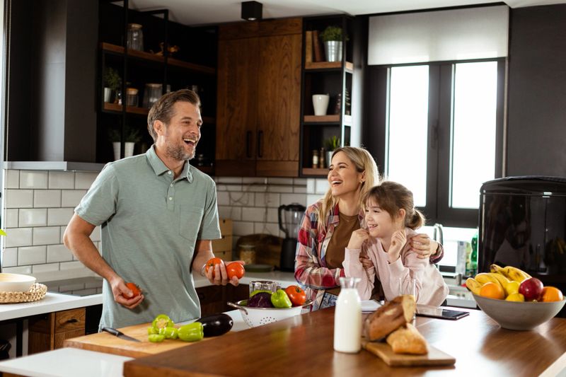 Young family chatting and preparing food around a bustling kitchen counter filled with fresh ingredients and cooking utensils