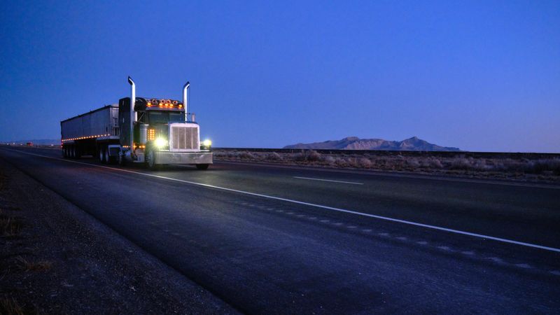 Large semi truck hauling freight on the open highway in the western USA at dawn.