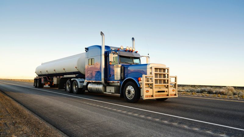 Large semi truck hauling freight on the open highway in the western USA under a morning sky.