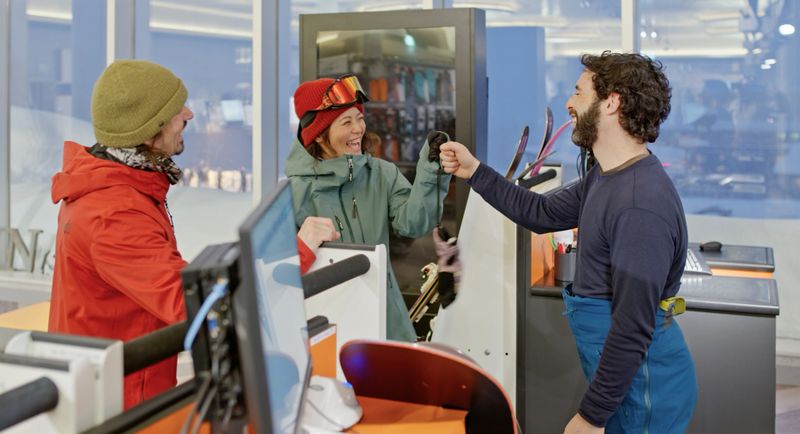White man and Japanese woman returning snowboards in the equipment rental shop at the ski lodge at the base of the mountain in Niseko, Japan.