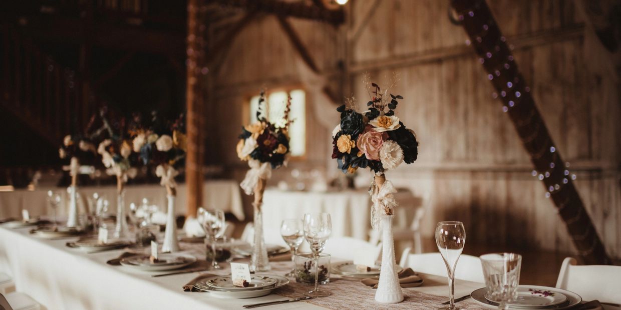 Cozy barn reception featuring white tablecloths and floral centerpieces