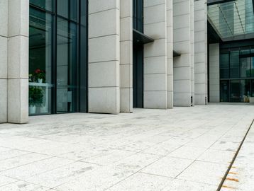 Modern building entrance with large glass windows and stone columns.