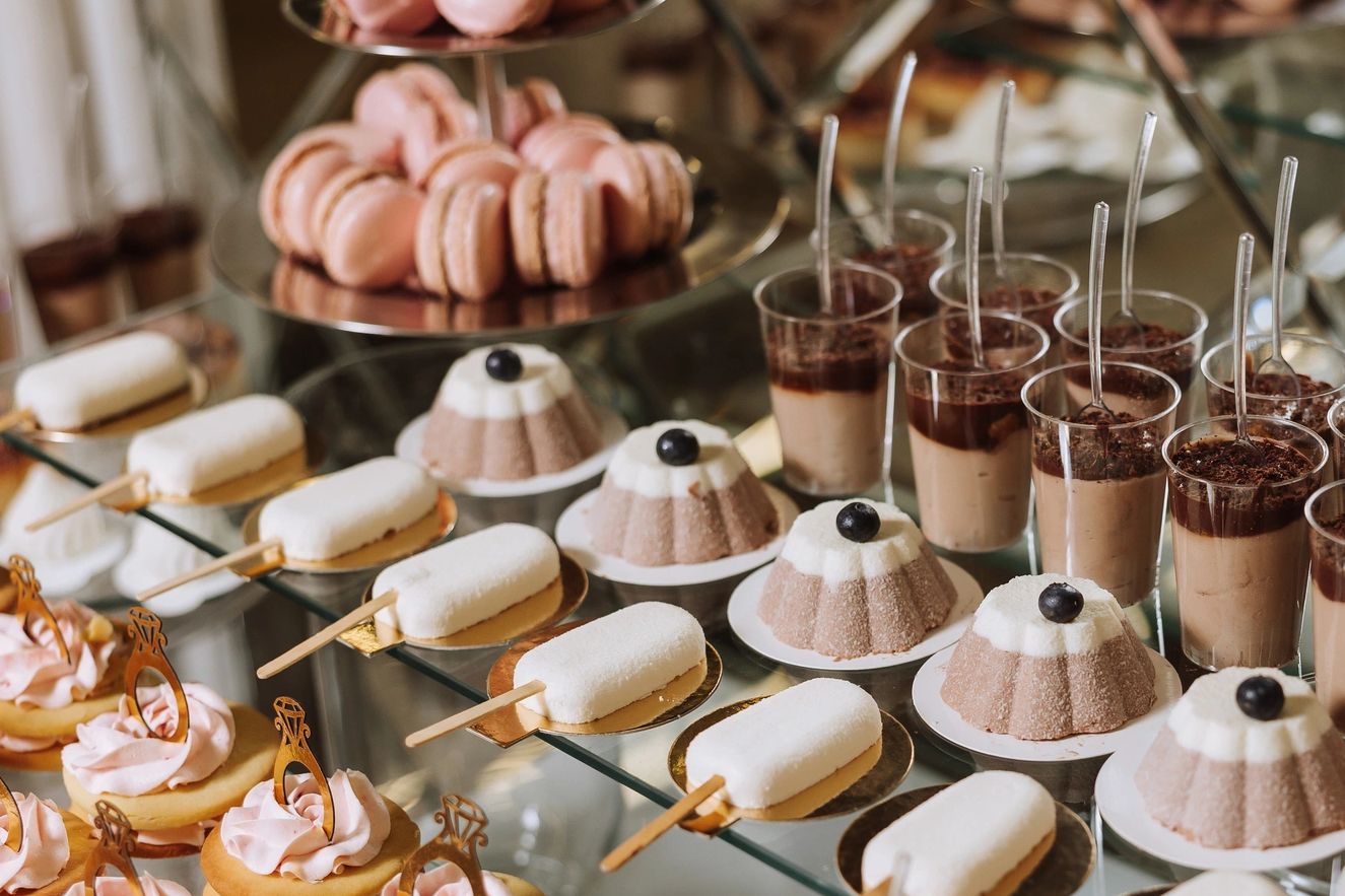 Assorted elegant desserts arranged on glass shelves.