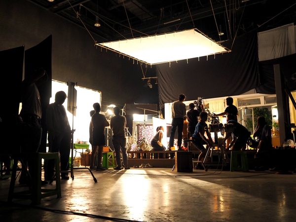 Film crew working on a set illuminated by professional lighting equipment.