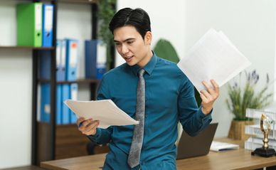 Man reading and holding documents in office.