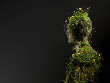 A human figure made of plants and flowers against a dark background.