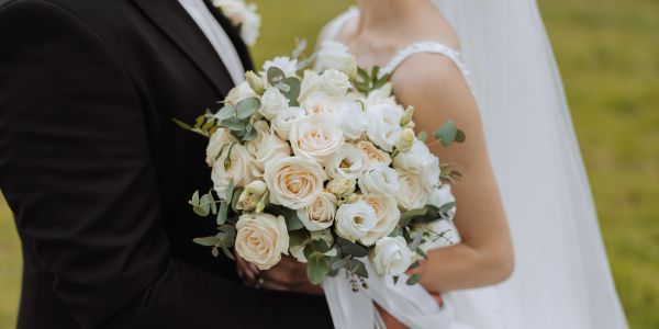 Bride and groom holding a floral bouquet.