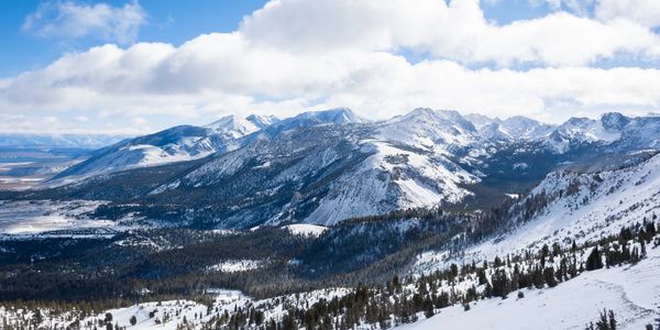 Snow-covered mountain range under a partly cloudy blue sky.
