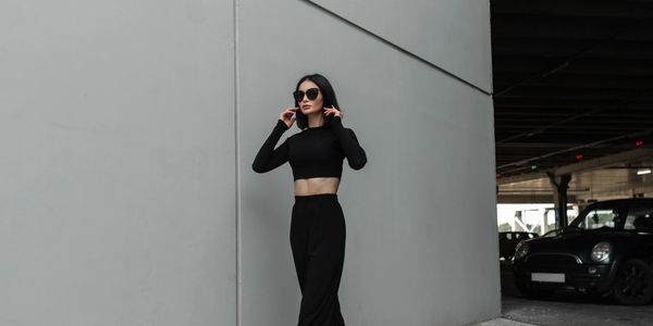Donna elegante in abiti neri con occhiali da sole.