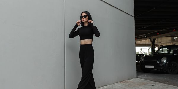 Donna elegante in abiti neri con occhiali da sole.