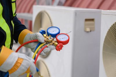 Technician using gauges to check HVAC system pressure.