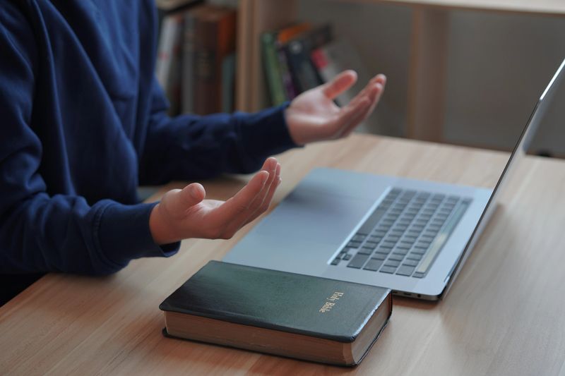 Religious man working on laptop at table.