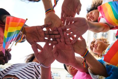 Group showing unity with rainbow flags and hands together.