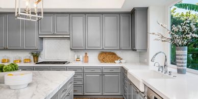 A kitchen with grey cabinets and white counter tops.