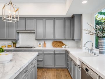 Modern kitchen with gray cabinets and white countertops.