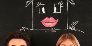 Chalk-drawn house with a face above two people's heads.
