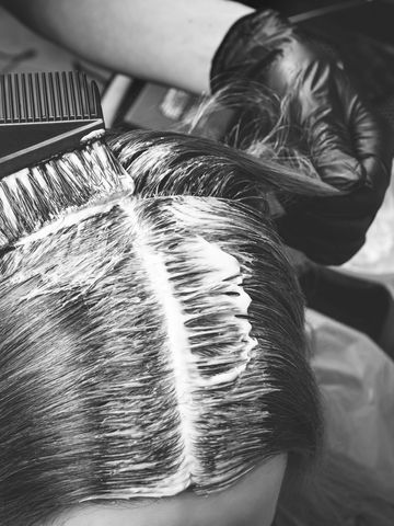 Hair being dyed with precision at the roots using a comb and brush.