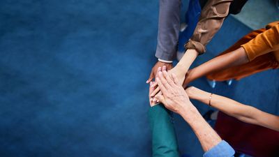 Hands stacked together symbolizing teamwork and unity.