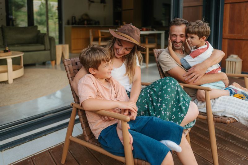 Photo of a young loving family, spending quality time together at the end of the busy week in front of their vacation home