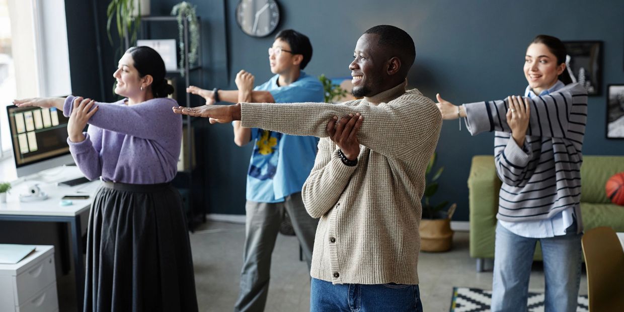 Four coworkers stretching together in an office.