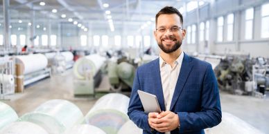 Confident man in suit with tablet in manufacturing facility.
