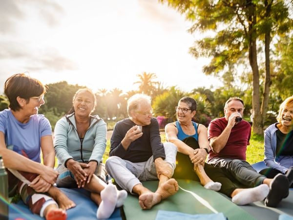 A group of seniors sitting outdoors, enjoying each other's company with smiles and laughter.